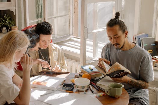 Group of college students collaborating and studying together on a sunny day in a dorm room.