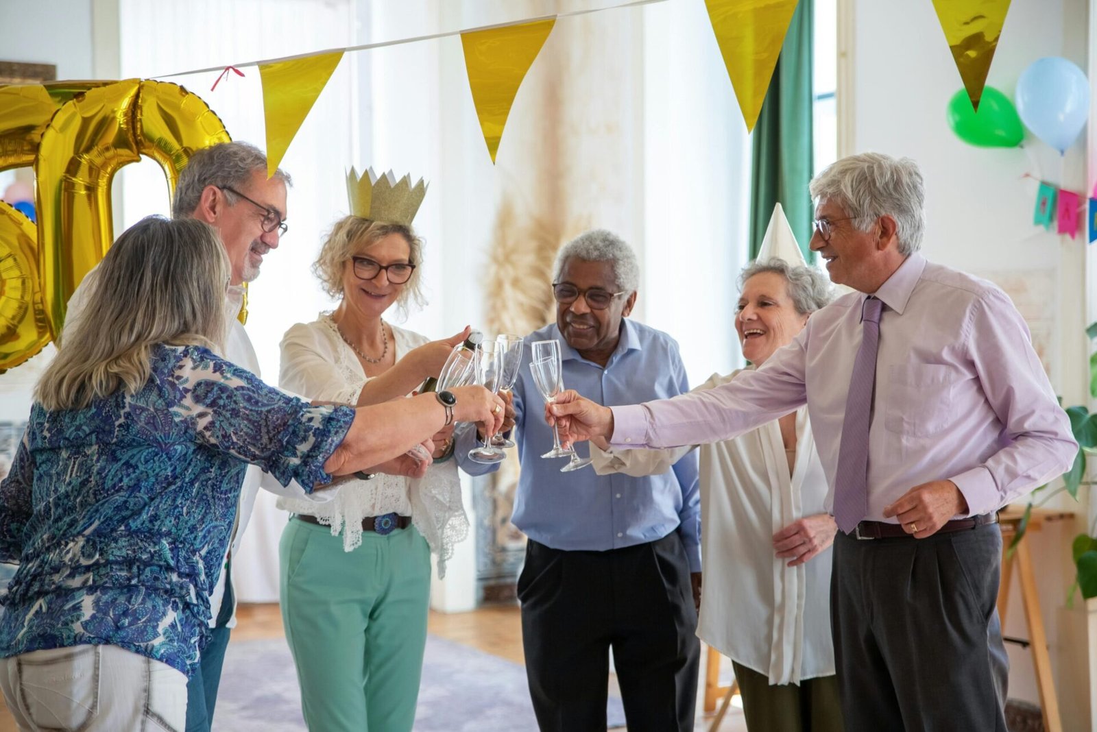 A group of elderly friends celebrating a birthday in Portugal with champagne and decorations.
